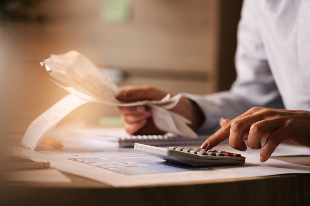 closeup economist using calculator while going through bills taxes office